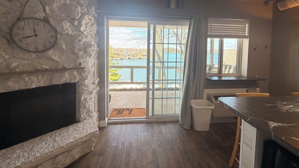 Quarto com parede de pedra, relógio, lareira, vista para um corpo d'água e janela com cortinas.