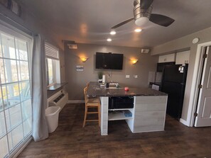 A modern kitchen with a central island, a ceiling fan, recessed lighting, and a built-in TV. - Adorable 1-bedroom condo with AC in Lake Ozark (Lake Ozark)