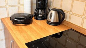 Una cocina equipada con cafetera, hervidor y una moderna cocina por inducción.