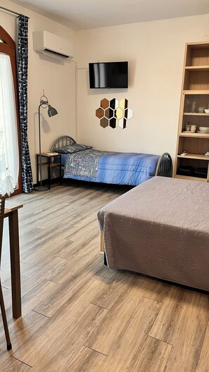 Ein Schlafzimmer mit Bett, Schreibtisch, Stuhl, Fernseher und Bücherregal.