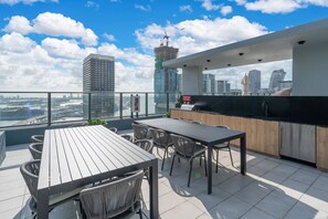 Une terrasse sur le toit avec une table et des chaises pour les repas, un coin cuisine et une vue sur la ville.