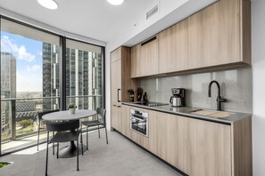 A modern kitchen with a large window, a dining area with a table and chairs, and a city view. - Sleek Corner 1BR | Rooftop Pool & Wrap Balcony (Miami)