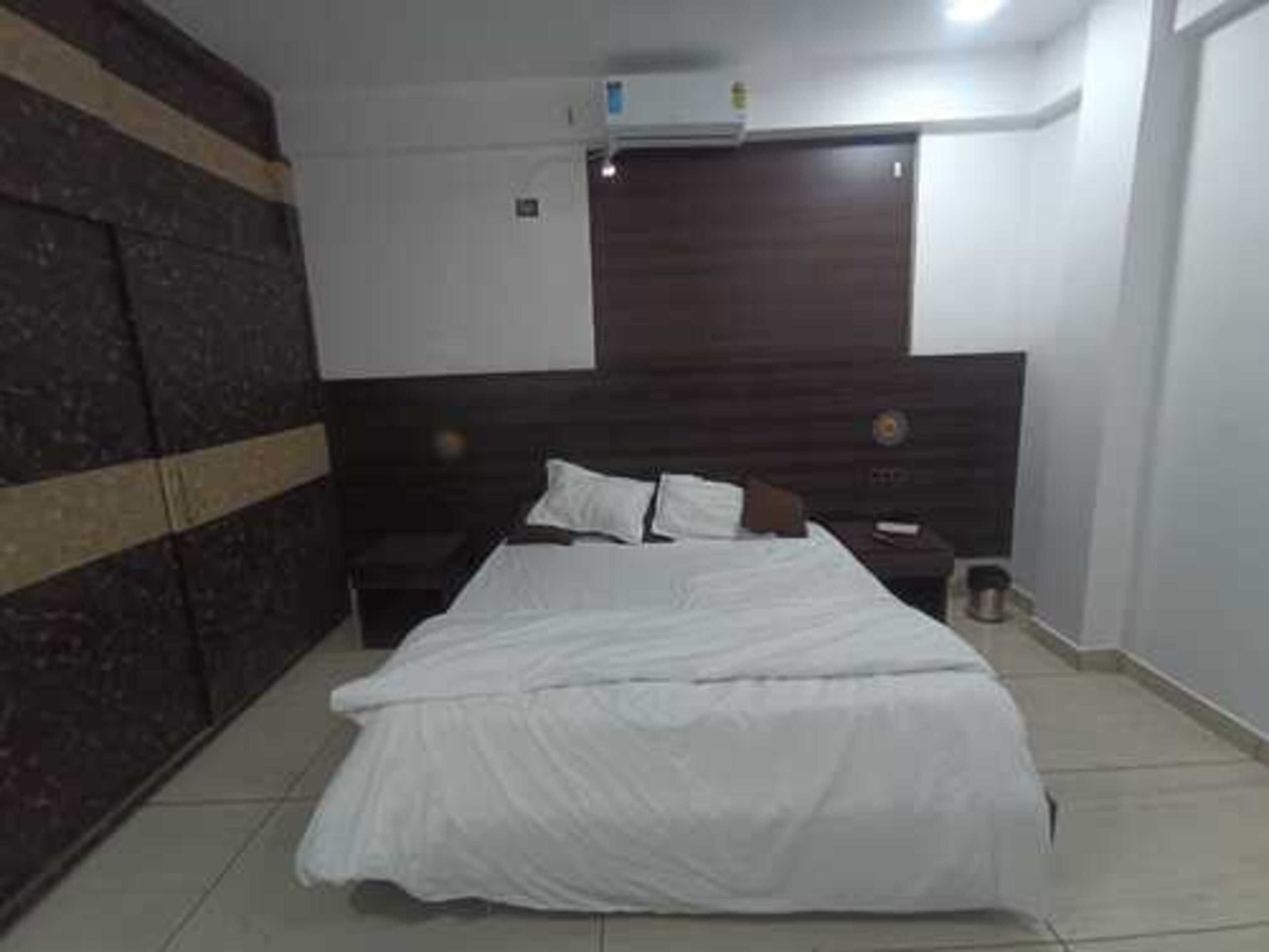 A bedroom with a bed, a nightstand, a wardrobe, and a wall-mounted air conditioner.