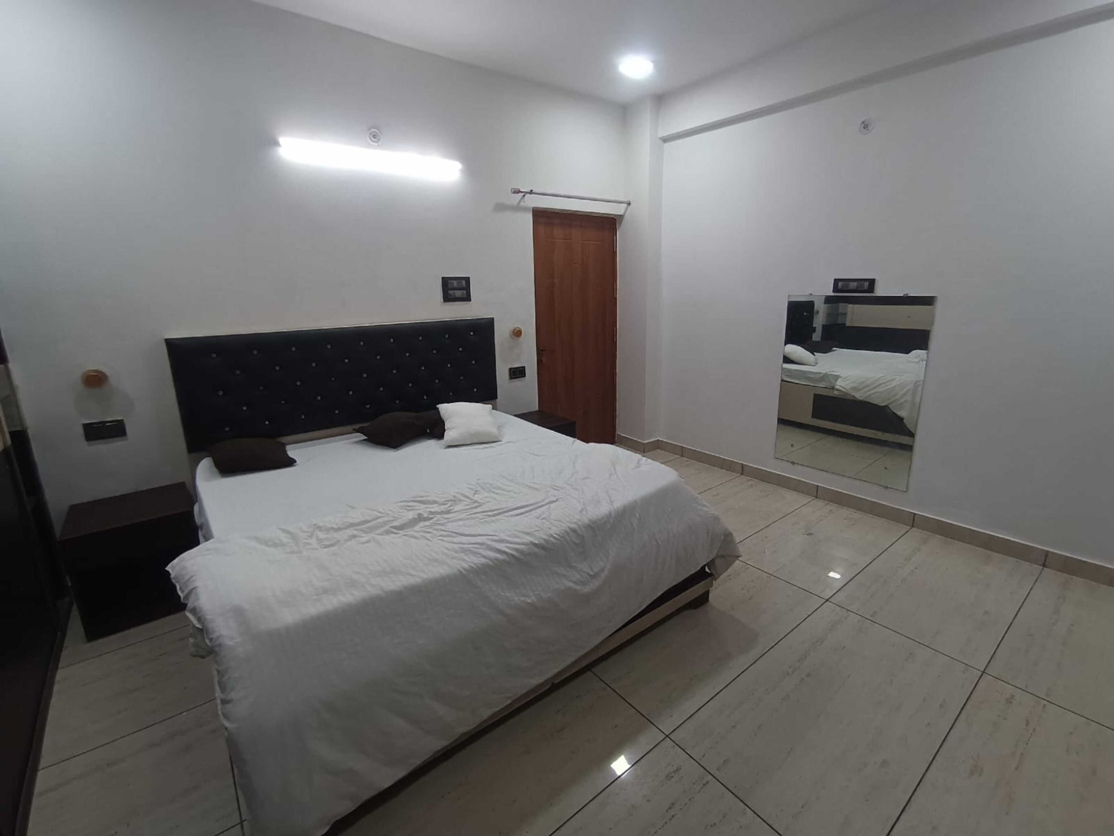 A bedroom with a bed, a nightstand, a mirror, and a ceiling light.