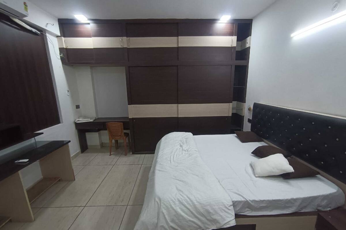 A bedroom with a bed, a desk, and a chair.