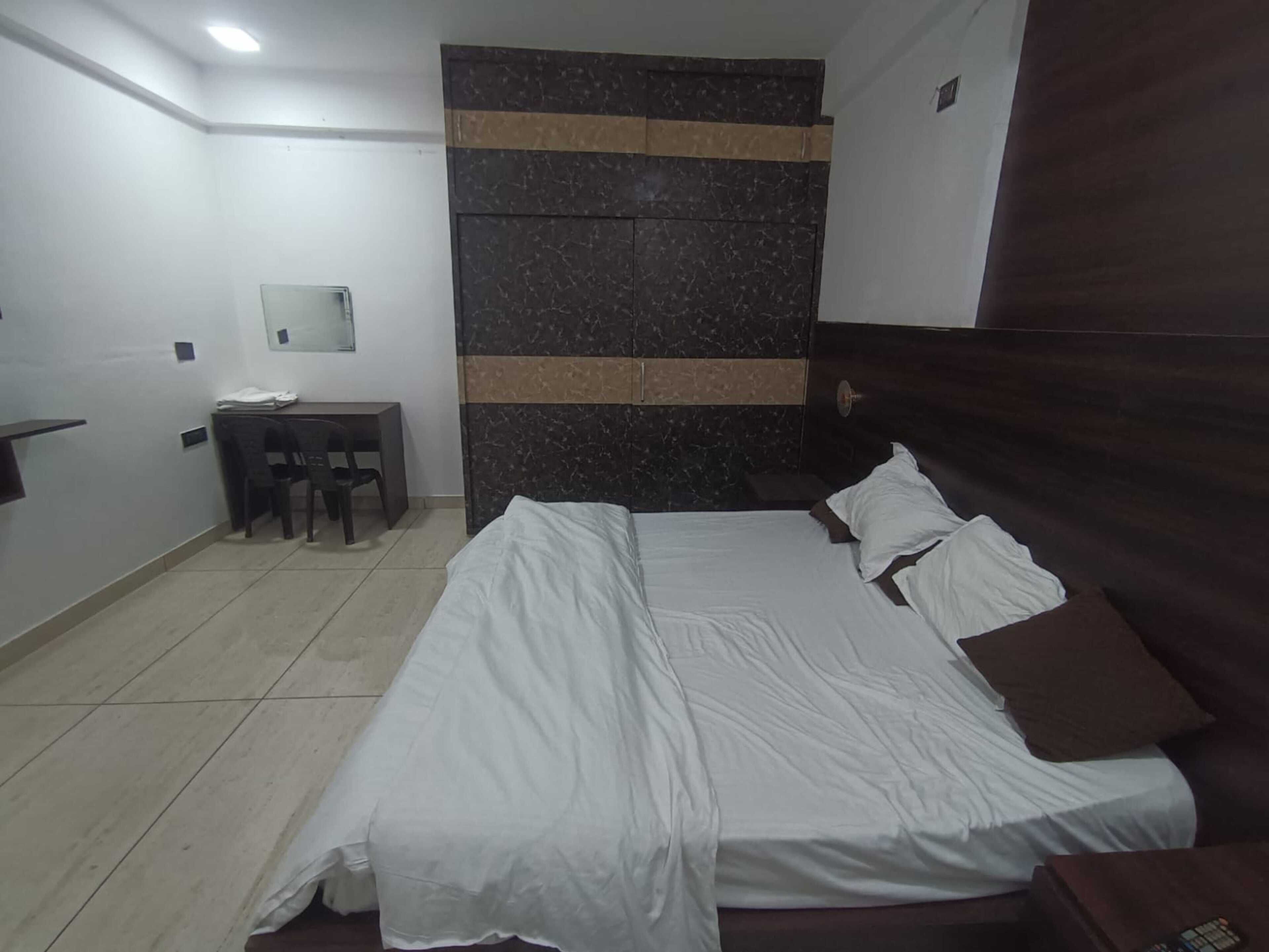 A bedroom with a bed, a desk, and a chair.