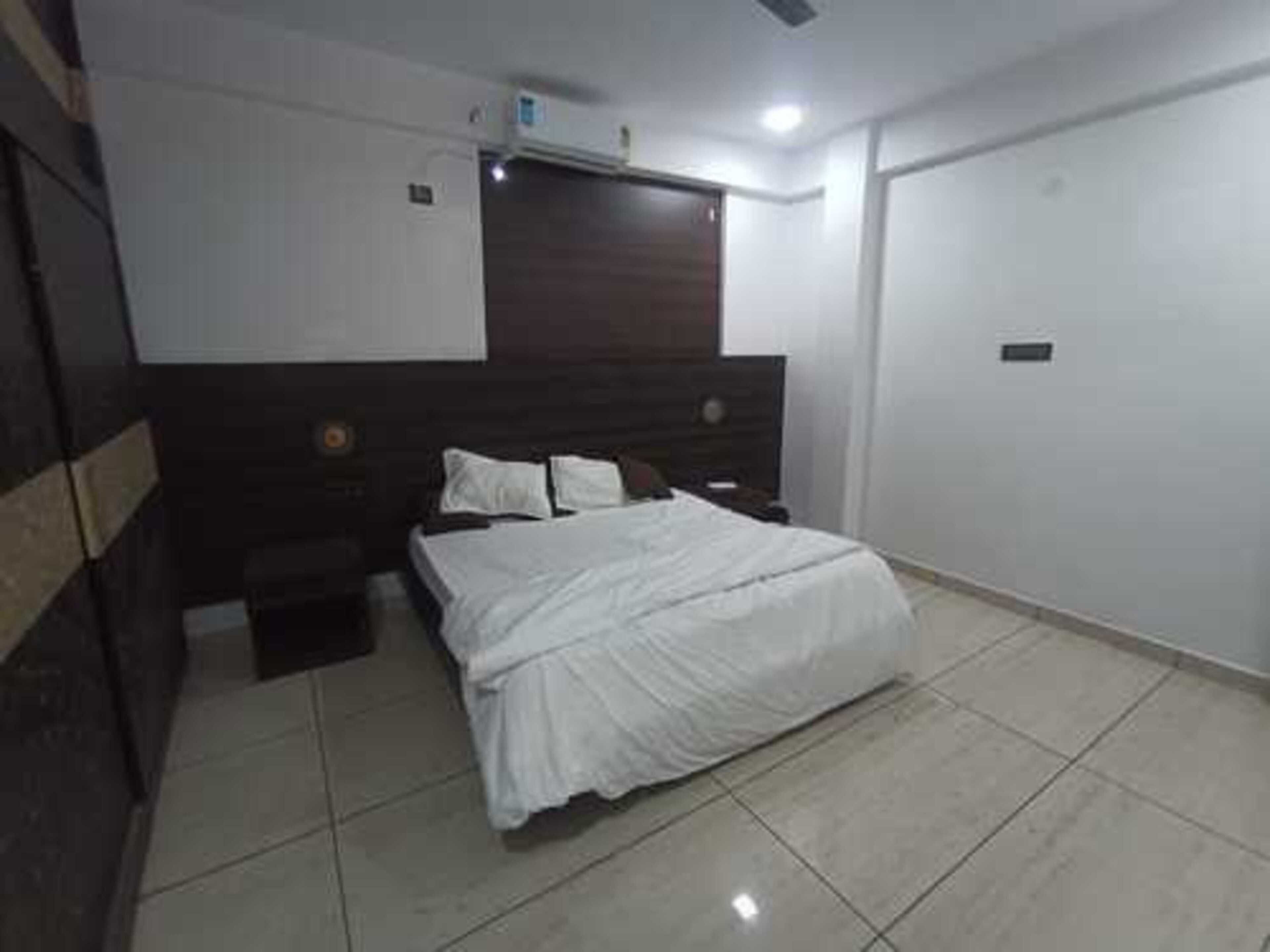 Un dormitorio con cama, mesita de noche, cómoda y aire acondicionado instalado en la pared.