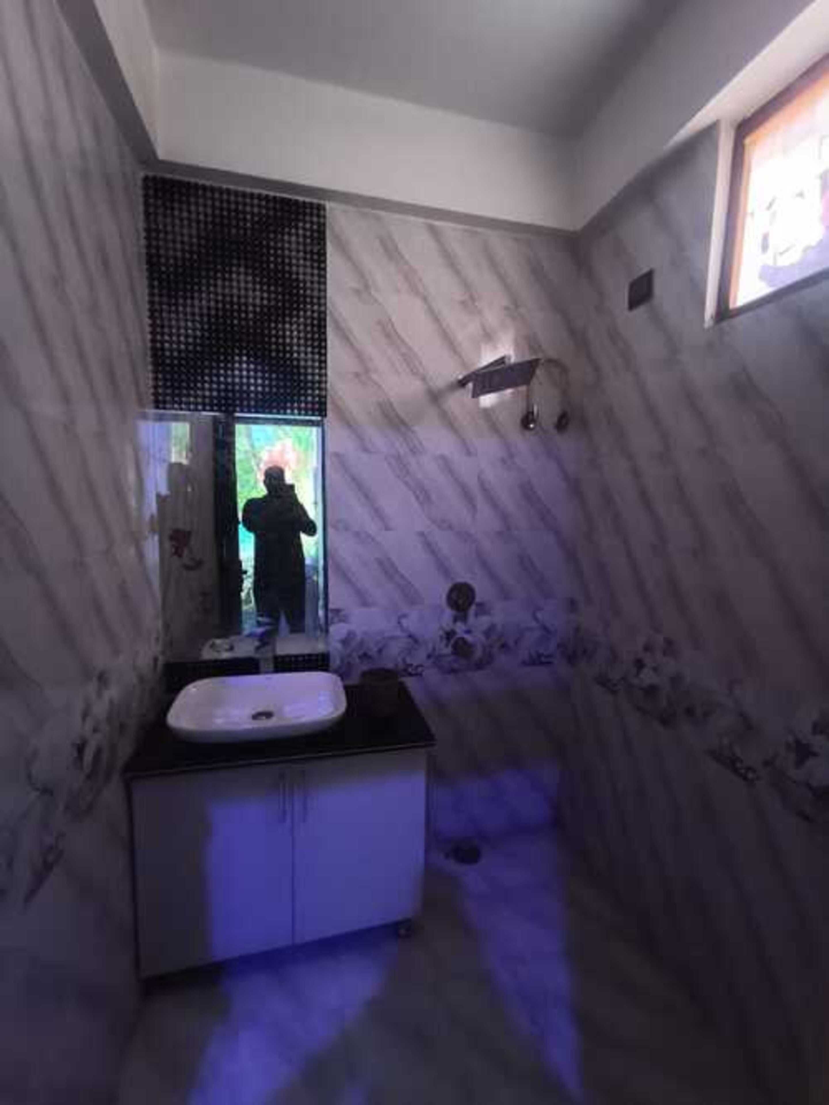 Une salle de bain avec un mur en marbre, un lavabo et un espace douche.