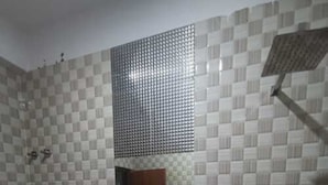 A bathroom with a white sink, a mirror, a shower, and a patterned wall. - Hotel Vivara (Lucknow)