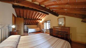 Ein Schlafzimmer mit einem großen Bett, Holzbalken, einem Schminktisch und einem Spiegel.