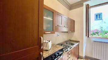 Una cocina compacta con armarios de madera, estufa y ventana con vistas a un jardín.