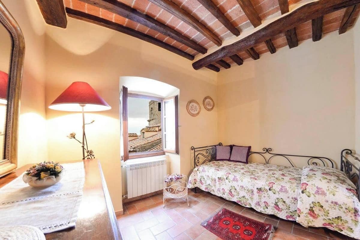 A bedroom with a bed, a window, a radiator, and a lamp.