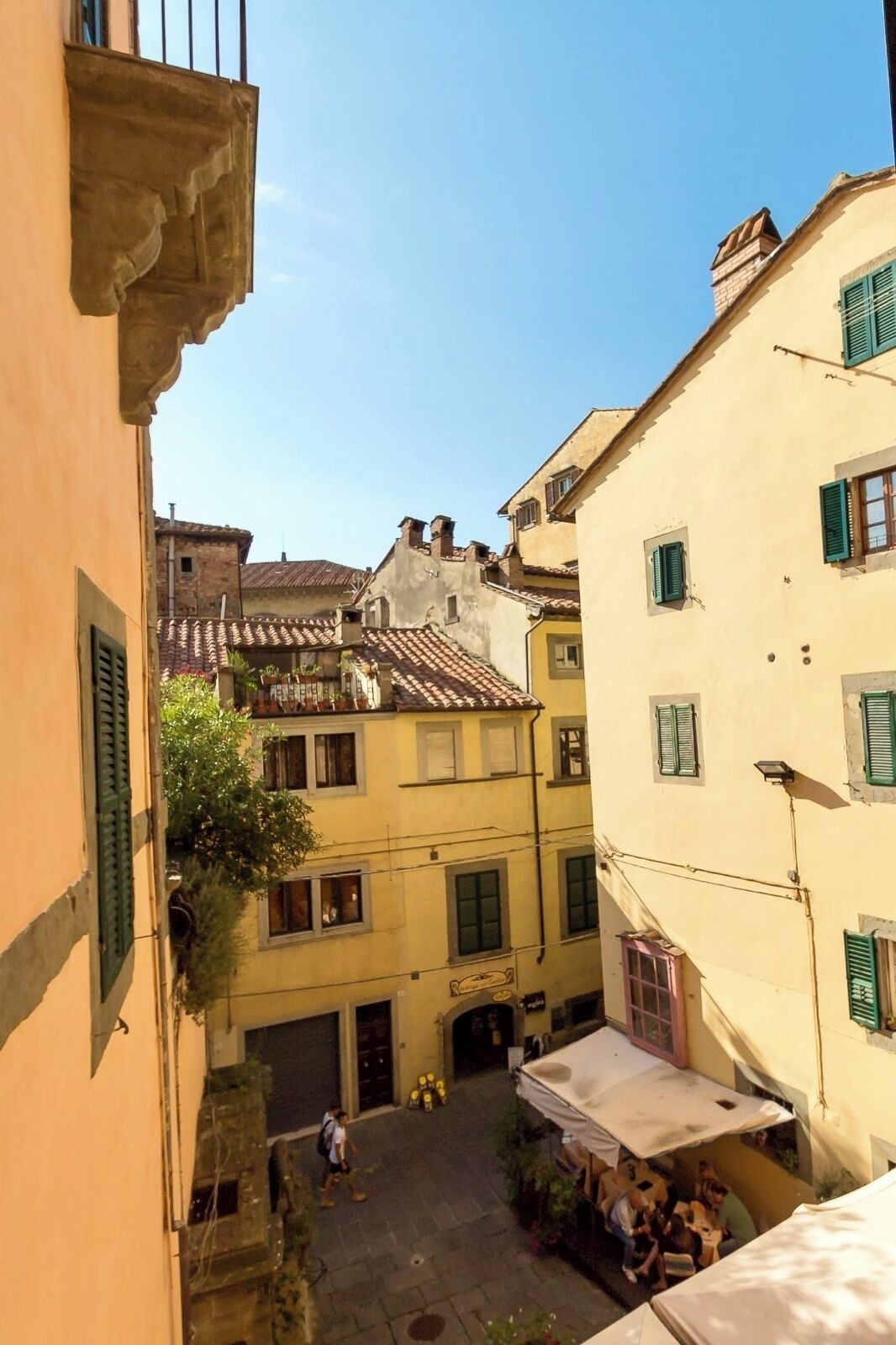 A narrow street with buildings on either side, featuring traditional architecture and a clear sky.