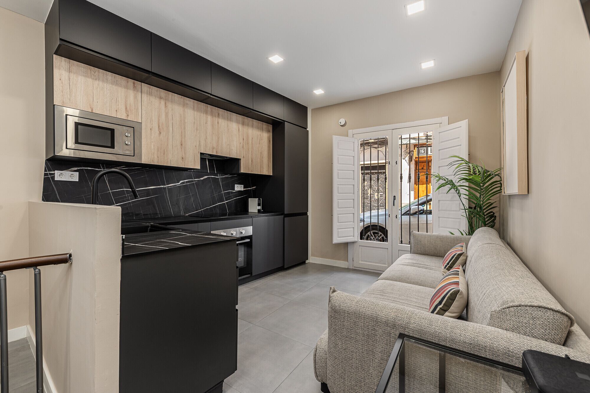 A modern kitchen with a built-in microwave, a black countertop, and wooden cabinets.