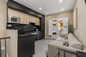 A modern kitchen with a built-in microwave, a black countertop, and wooden cabinets. - Waou Essence II El Rastro - Short-Term (Madrid)