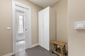 A hallway with a white door, a white wardrobe, and a wooden stool. - Waou Essence II El Rastro - Short-Term (Madrid)