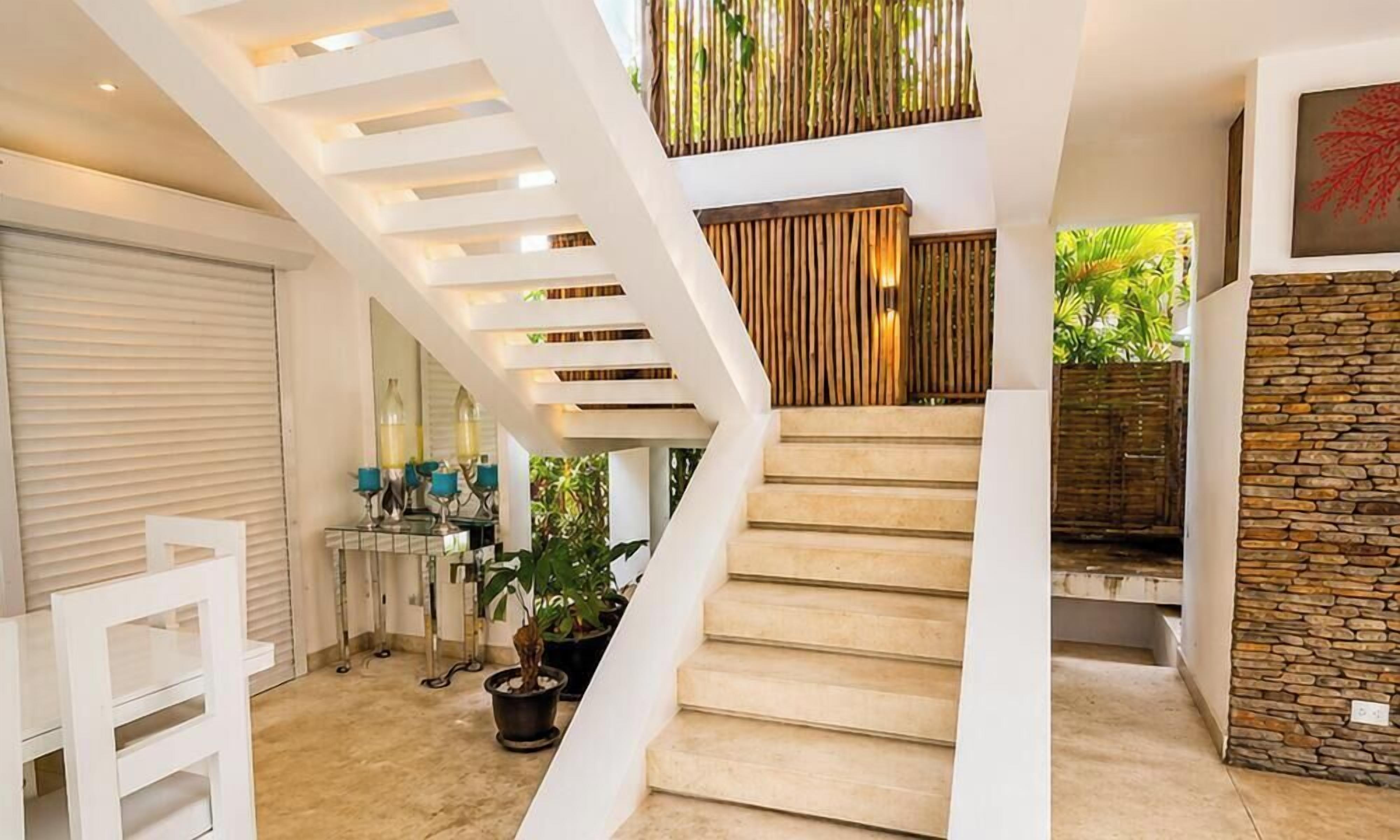 Eine moderne Treppe mit weißen Geländern, einer Steinsäule und einem Blumentopf.