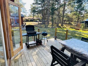 An outdoor deck with a grill, a table, and chairs, overlooking a forested area. - 4 Person Holiday Home in Yngsjo (Yngsjo)