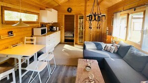 A cozy cabin interior with a dining area, sofa, and a chandelier. - 4 Person Holiday Home in Yngsjo (Yngsjo)