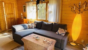 A cozy log cabin room with a sectional sofa, a small table, and a floor lamp. - 4 Person Holiday Home in Yngsjo (Yngsjo)