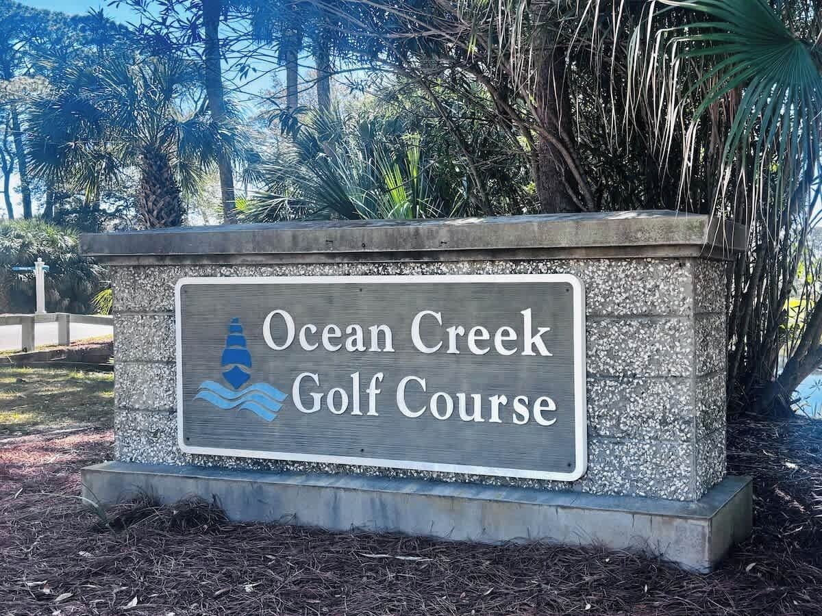 En skylt för Ocean Creek golfbana, med en logotyp som föreställer en golfboll och en flagga.
