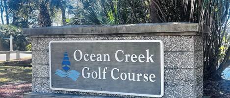 En skylt för Ocean Creek golfbana, med en logotyp som föreställer en golfboll och en flagga.