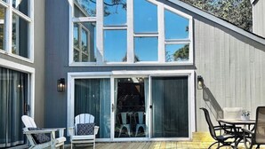 Een modern huis met een terras, schuiframen en tuinmeubilair.