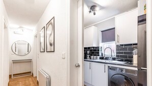 A modern kitchen with a washing machine, a built-in oven, and a sink. - City & Sea: Cosy retreat (Great Yarmouth)