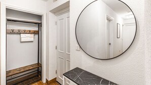 A hallway with a coat closet, a round mirror, and a small vanity table. - City & Sea: Cosy retreat (Great Yarmouth)