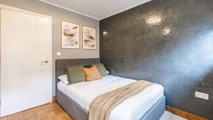 A bedroom with a bed, a door, and a wall with a textured finish. - City & Sea: Cosy retreat (Great Yarmouth)
