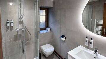 Une salle de bain moderne avec une douche à parois de verre, des toilettes, un lavabo et un miroir.