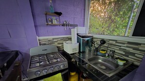 A compact kitchen with a gas stove, a sink, and a window with a view of greenery. - The best modern apartment in Santa Ana with private movie theater and fast internet (Santa Ana)