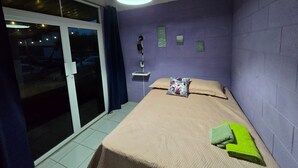A bedroom with a bed, a nightstand, a lamp, and a view through a sliding door. - The best modern apartment in Santa Ana with private movie theater and fast internet (Santa Ana)