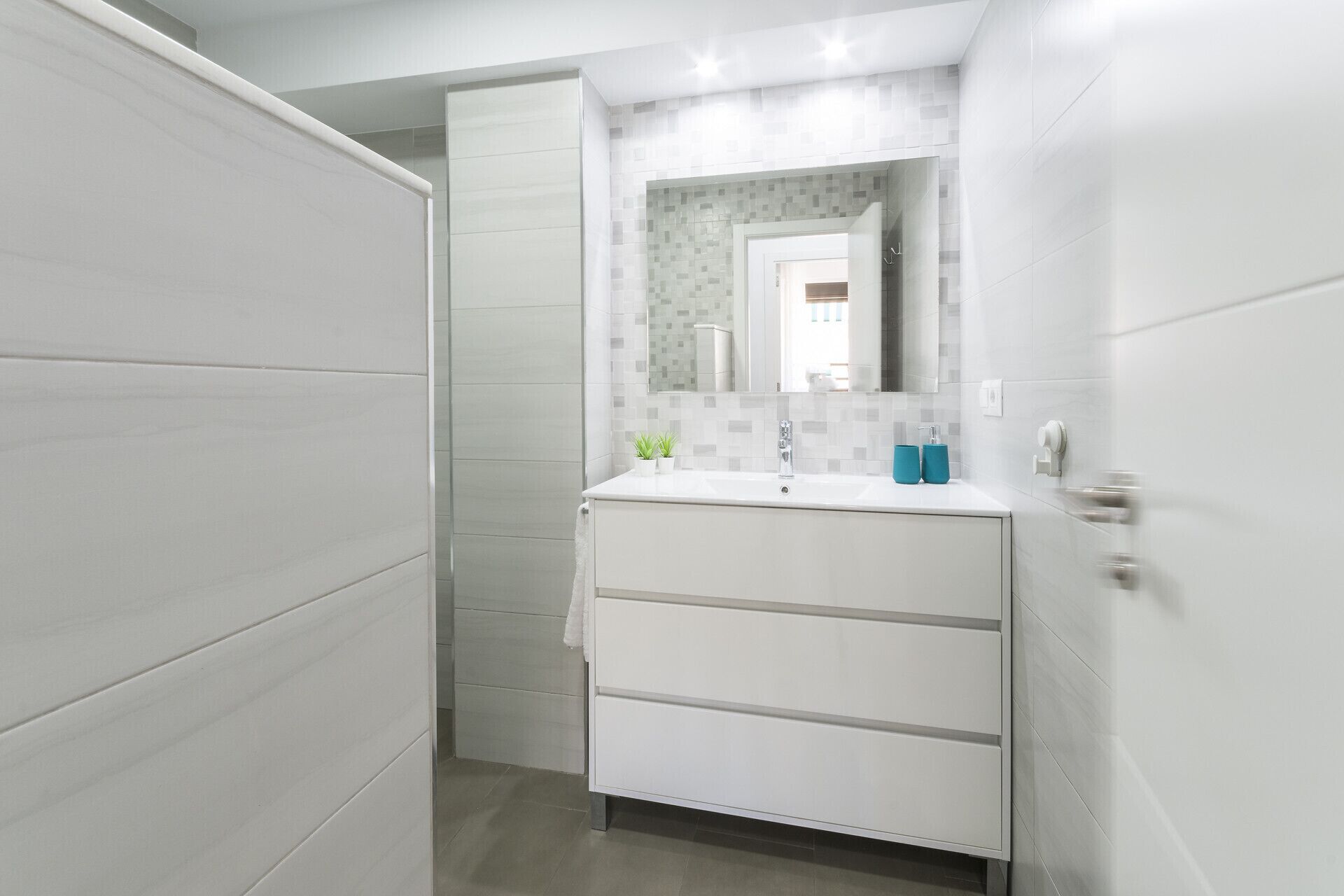 A bathroom with a white vanity, a mirror, and a tiled backsplash.