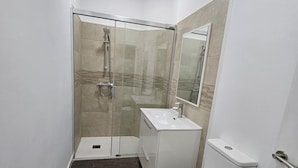 Un bagno moderno con cabina doccia in vetro, lavandino bianco e water.