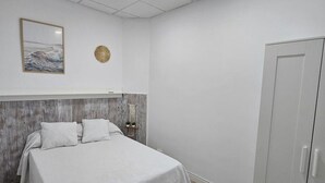 Una camera da letto con un letto, un armadio, una lampada a soffitto e un addobbo murale.