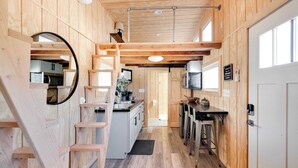 Een compacte keuken met houten wanden, een centraal kookeiland en een klein zithoekje.