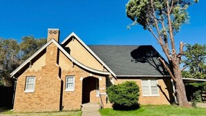 A two-story brick house with a gabled roof, a chimney, and a front entrance. - 6BR Sleep 20 DT Amarillo Tech/Data Ctr Corp Stays (Amarillo)