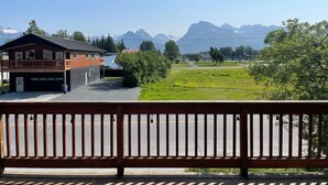 A building with a balcony overlooking a grassy area and mountains. - Relax comfortably & enjoy a 2-bedroom studio in Valdez perfect for your getaway. (Valdez)
