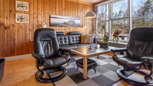 A wooden-paneled room with a sofa, two chairs, a table, and a painting on the wall. - "Eivi" - 200m from the sea by Interhome (Væggerløse)