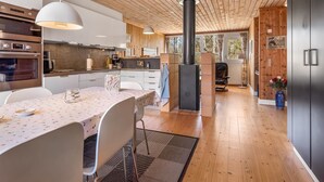 A modern kitchen with wooden ceiling, a central stove, and a dining area with a table and chairs. - "Eivi" - 200m from the sea by Interhome (Væggerløse)
