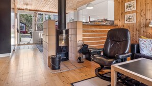 A modern interior with a wood-paneled ceiling, a fireplace, a leather chair, and a dining area. - "Eivi" - 200m from the sea by Interhome (Væggerløse)