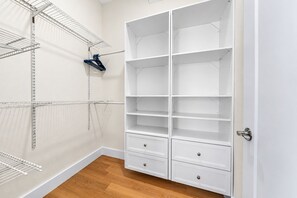 Un dressing accessible sans porte, doté d’étagères ouvertes, d’un étendoir métallique et d’une porte avec une poignée.