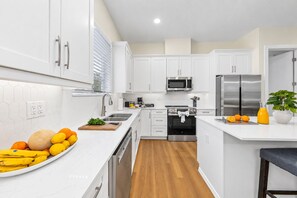 Une cuisine moderne avec des armoires blanches, des appareils en acier inoxydable et un plancher en bois.