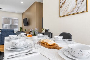 A dining area with a table set for four, including plates, bowls, glasses, and cutlery. - Private Patio | Ground Floor | Near Busch Gardens (Tampa)