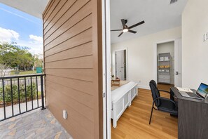 A room with a bed, a desk with a laptop, a ceiling fan, and a view of the outdoors. - Private Patio | Ground Floor | Near Busch Gardens (Tampa)