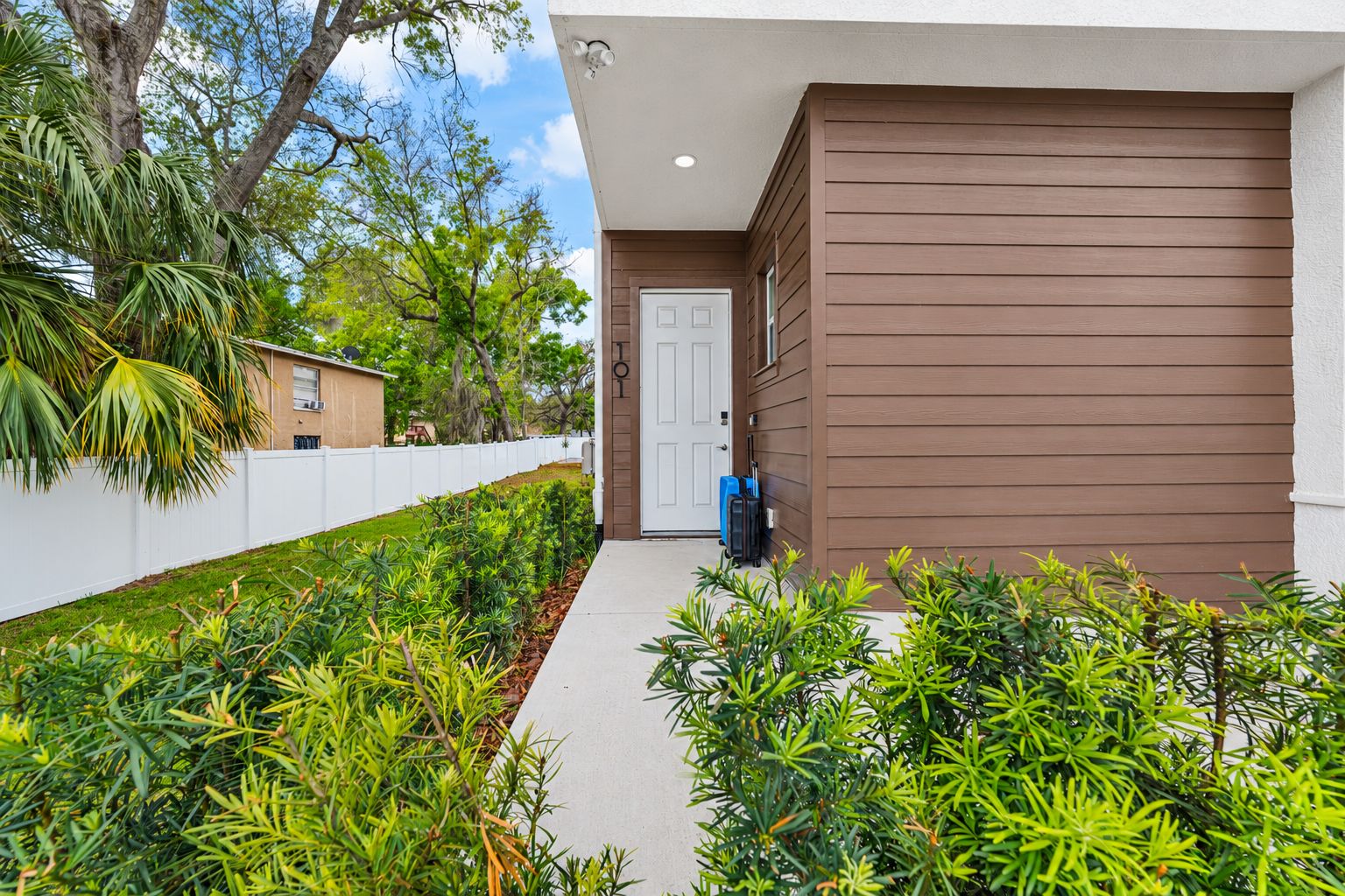 A modern building with a brown exterior, a white door, and a pathway leading to the entrance.