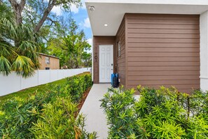 Un bâtiment moderne à l’extérieur brun, avec une porte blanche et un chemin menant à l’entrée.