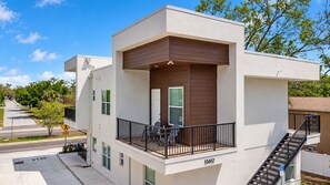 Un bâtiment moderne doté d’un balcon, d’un escalier et d’un numéro de maison bien visible.