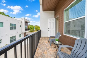 A balcony with stone flooring, a door, and two chairs. - Bright & Modern 3BR Home – Prime Tampa Location (Tampa)